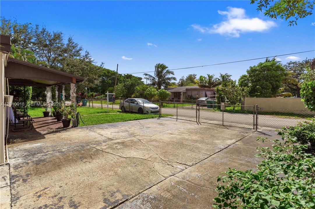 Concrete driveway, chain-link perimeter fencing, and covered outdoor patio area