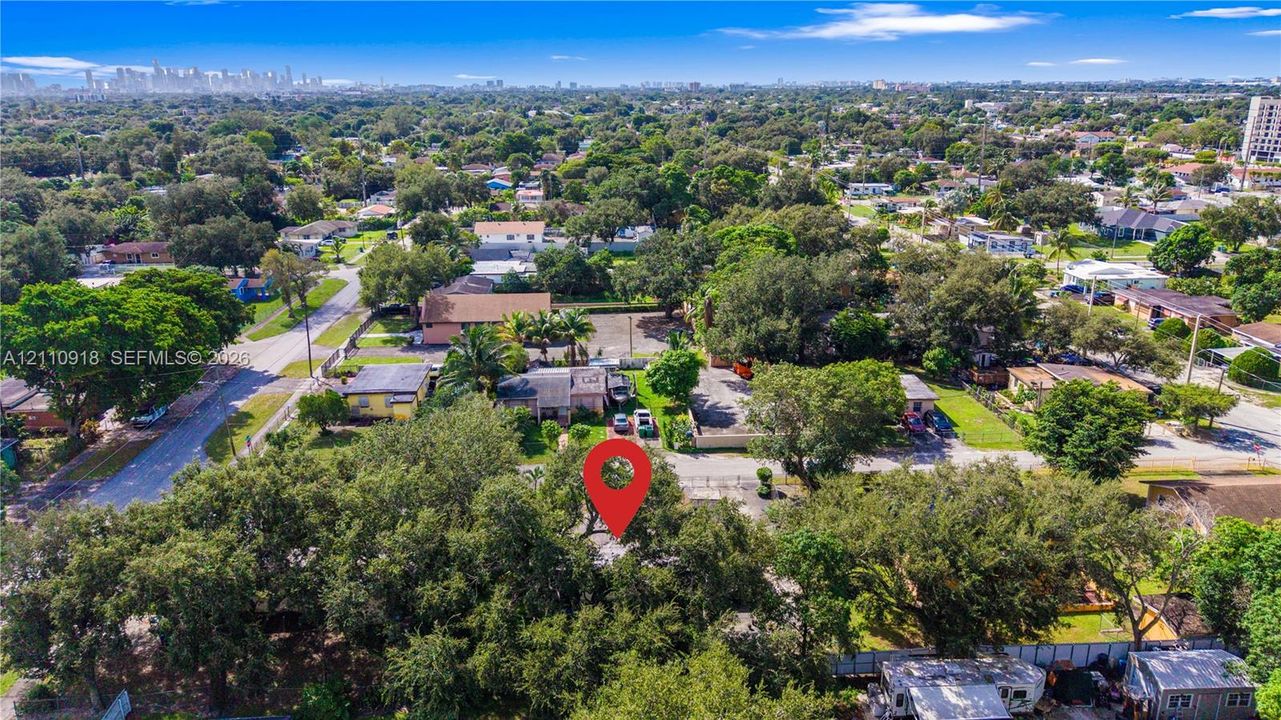 Aerial perspective showcasing a parcel of land featuring mature canopy trees and an urban skyline backdrop