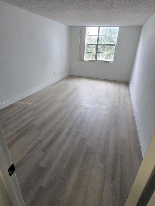 Neutral interior featuring wood-finish flooring, white walls, and a multi-pane window
