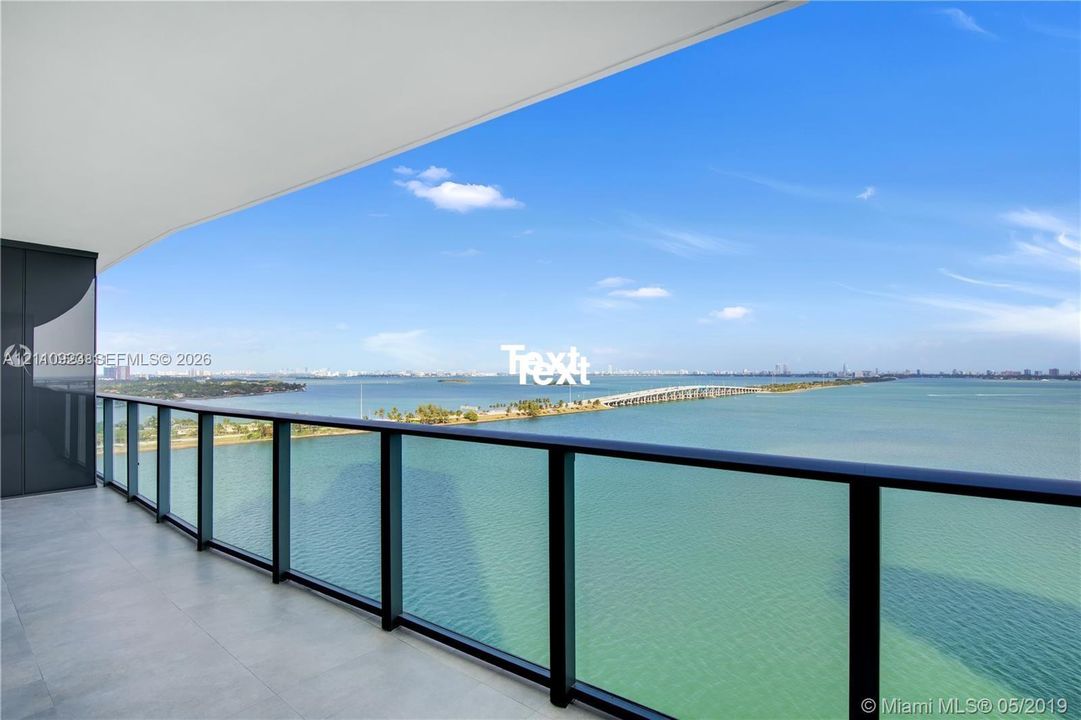 Covered terrace featuring large-format tile flooring and a glass-paneled railing with black framing