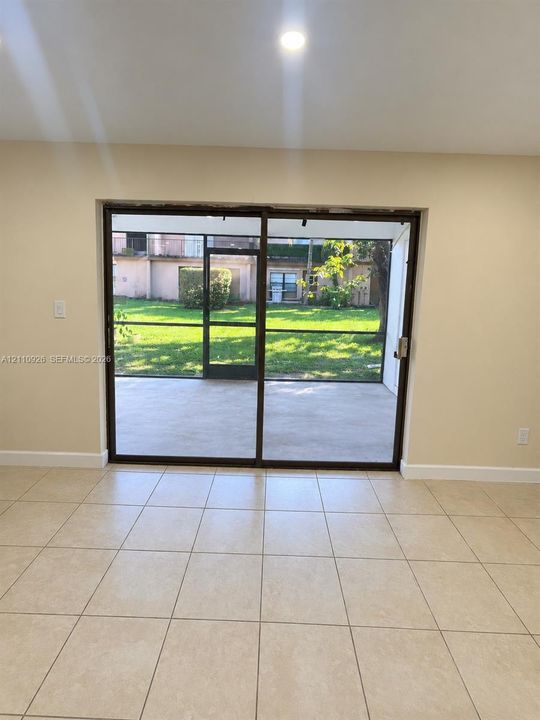 Large-format ceramic tile flooring, recessed ceiling lighting, and sliding glass doors opening to a screened-in lanai with concrete patio surfacing