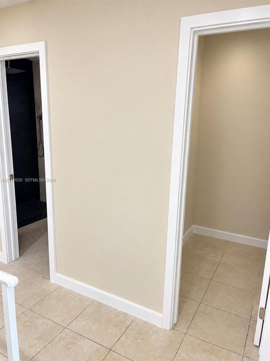 Tiled flooring, high-contrast dark interior shower wall, and minimalist casing trim