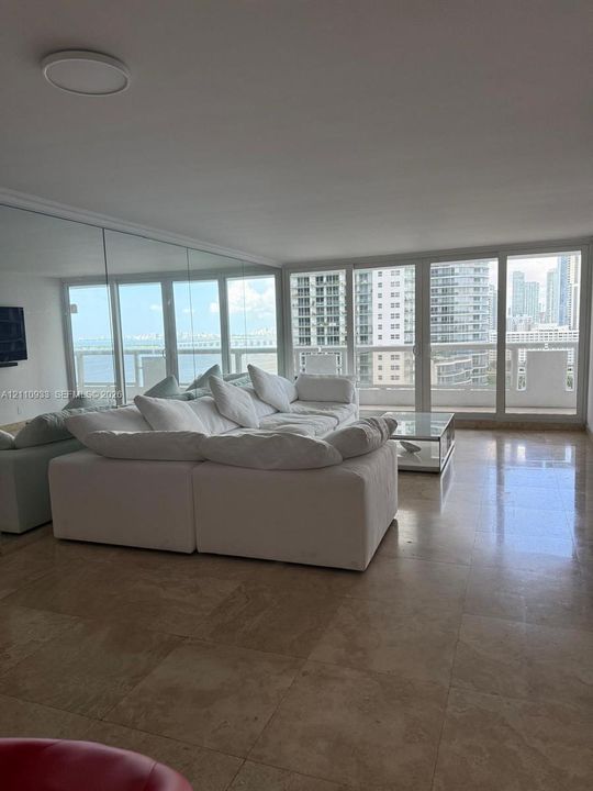 Stone tile flooring, wall-to-wall mirrored surfacing, and floor-to-ceiling windows with access to a glass-railed balcony
