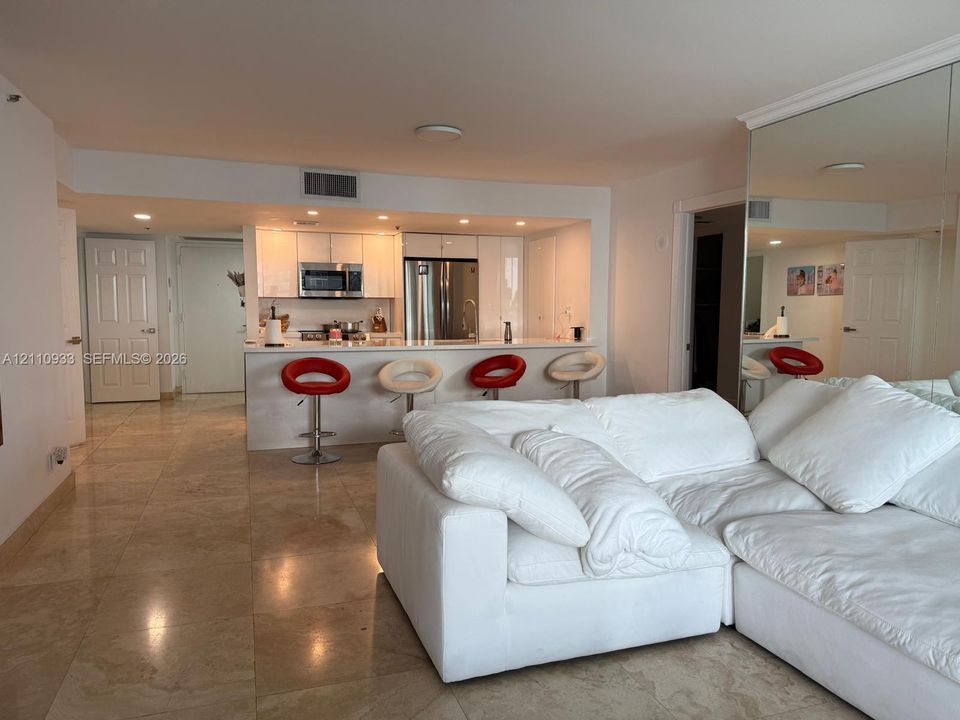 Open kitchen featuring white cabinetry, stainless steel appliances, and stone-finish countertops with a breakfast bar