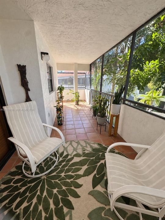 Screened-in porch featuring ceramic tile flooring, metal railings, and a wall-mounted light fixture
