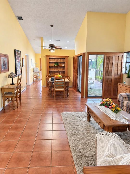 Vaulted ceilings, ceramic tile flooring, built-in wooden shelving, and sliding glass doors with shutter-style privacy panels