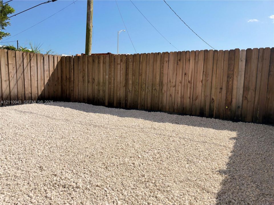 Fenced outdoor area featuring a full-height wood privacy fence and decorative gravel ground cover