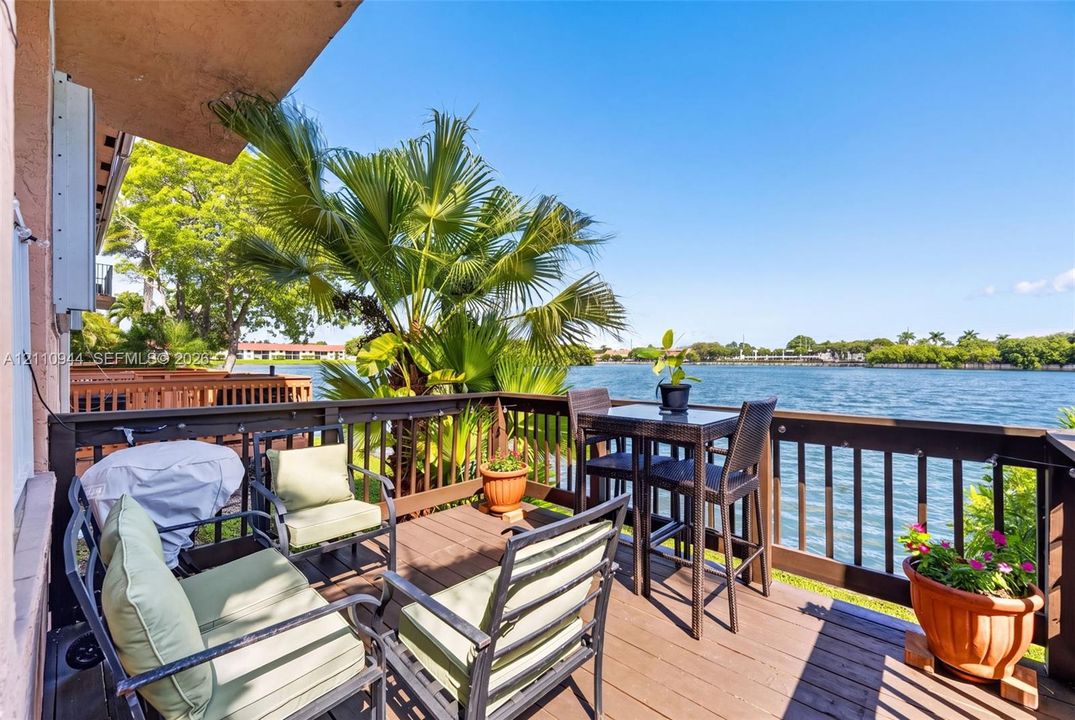 Elevated exterior deck featuring wood-finish decking and dark-finished railing, overlooking a large waterfront expanse