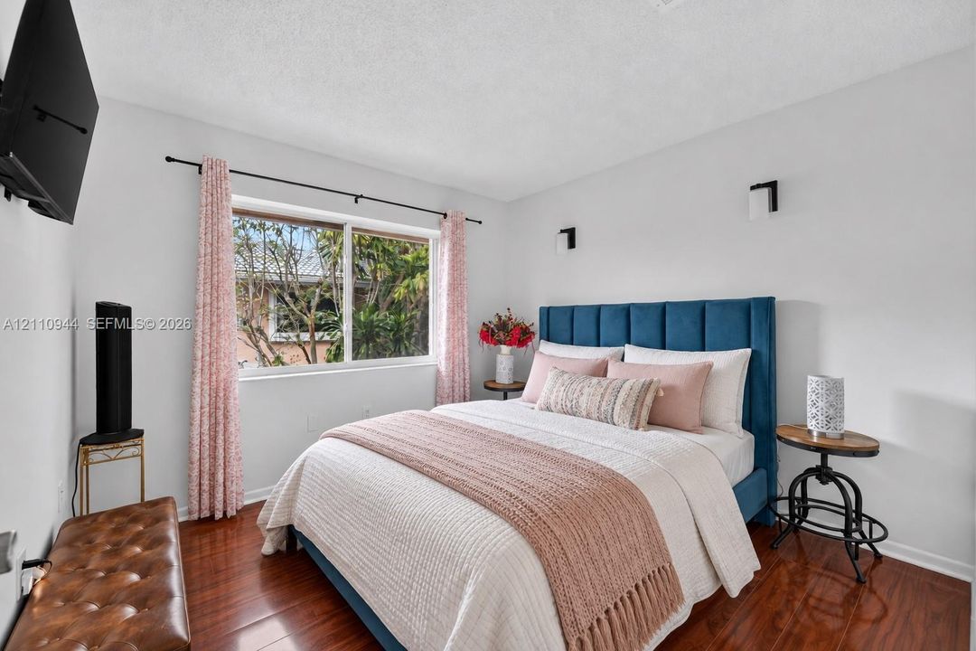 Wood-finish flooring, dual wall-mounted sconce lighting, and a large picture window
