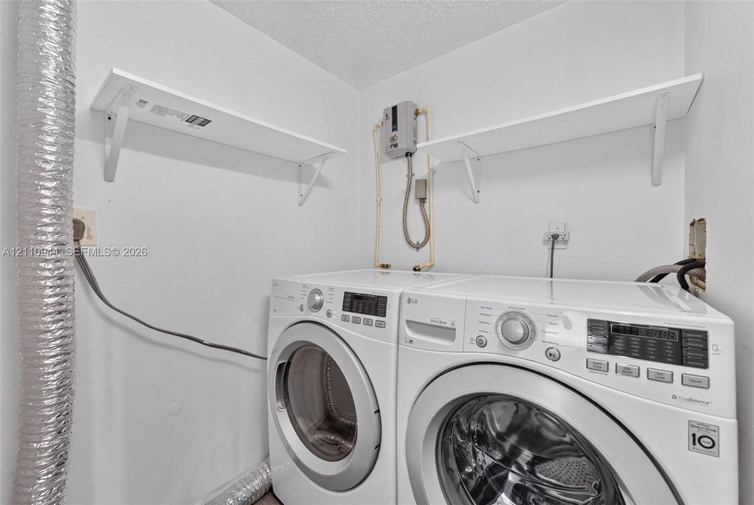 Utility space featuring wall-mounted shelving and dedicated hookups for laundry appliances