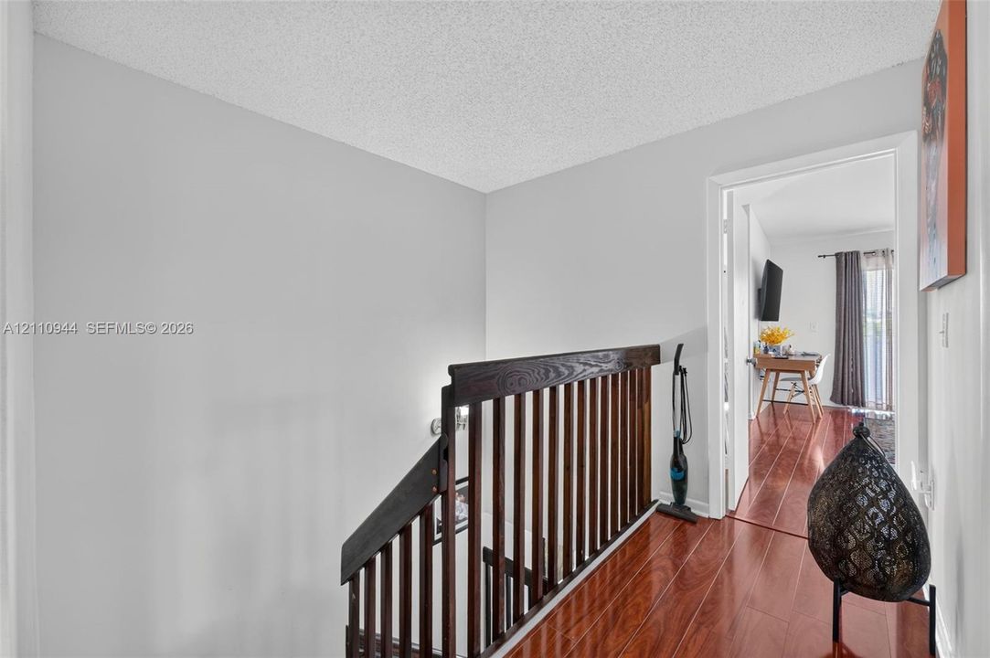 Stairwell featuring a dark wood-finish railing with vertical balusters and wood-finish flooring
