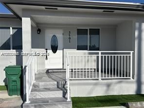 Covered porch entrance with tile stairs, white metal railings, and a central oval-insert front door