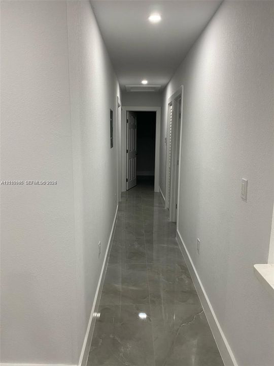 Hallway featuring large-format tile flooring, recessed ceiling lighting, and crisp white wall finishes