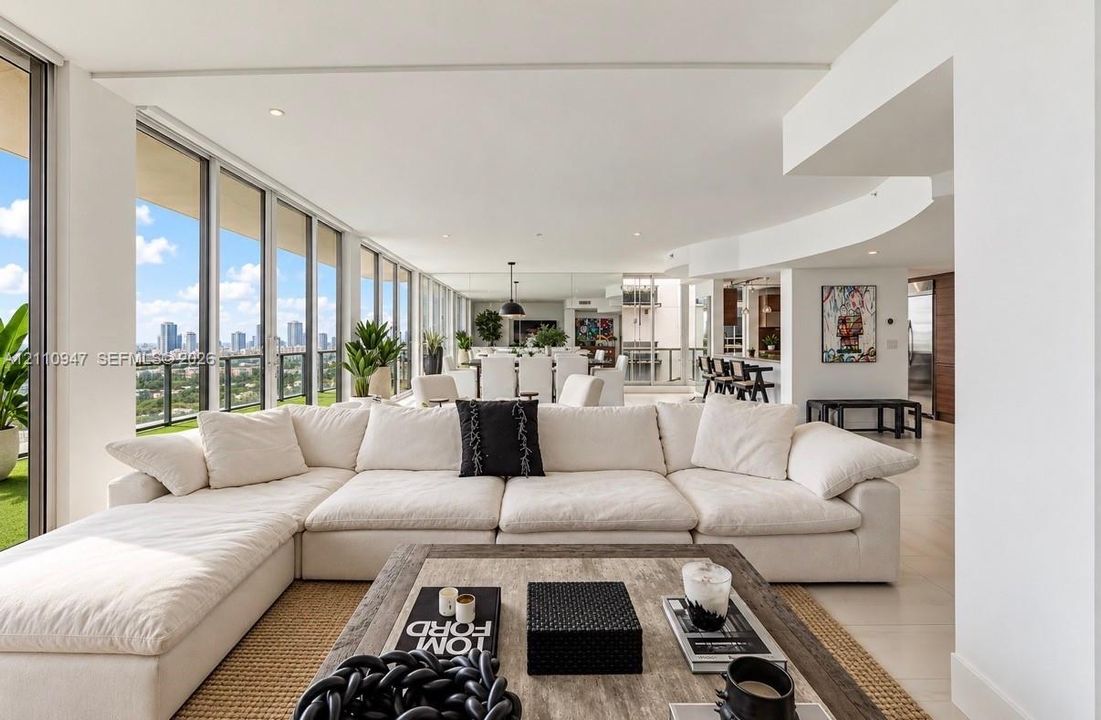Floor-to-ceiling glass windows, recessed ceiling lighting, light-toned tile flooring, and a curved architectural wall design