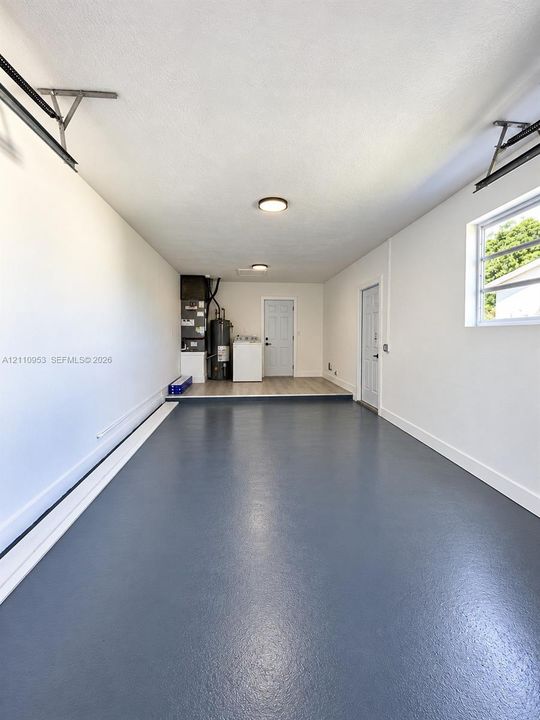 Attached two-car garage featuring sealed epoxy flooring, recessed ceiling lighting, and a window with horizontal panes