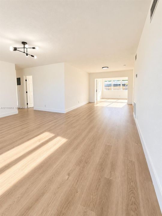 Open interior space featuring wood-finish flooring, neutral walls, and a multi-arm geometric ceiling fixture