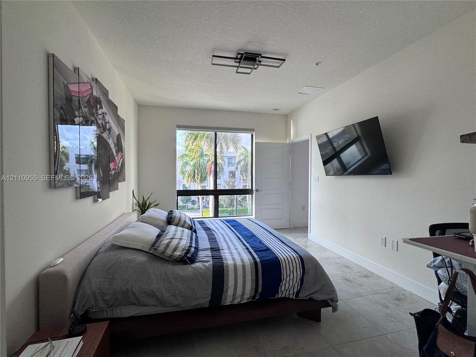 Large format tile flooring, contemporary geometric ceiling light fixture, and floor-to-ceiling window framing exterior landscape
