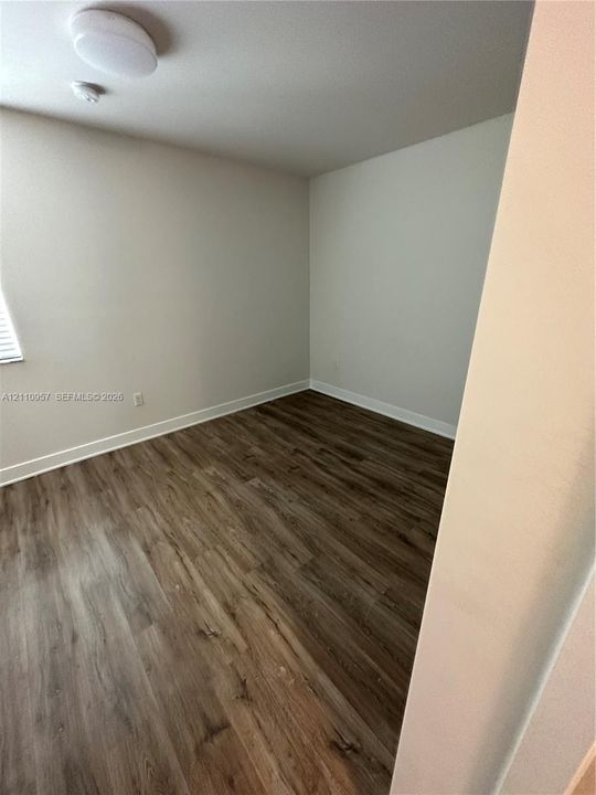 Room with wood-finish flooring, neutral-toned walls, and a ceiling-mounted light fixture