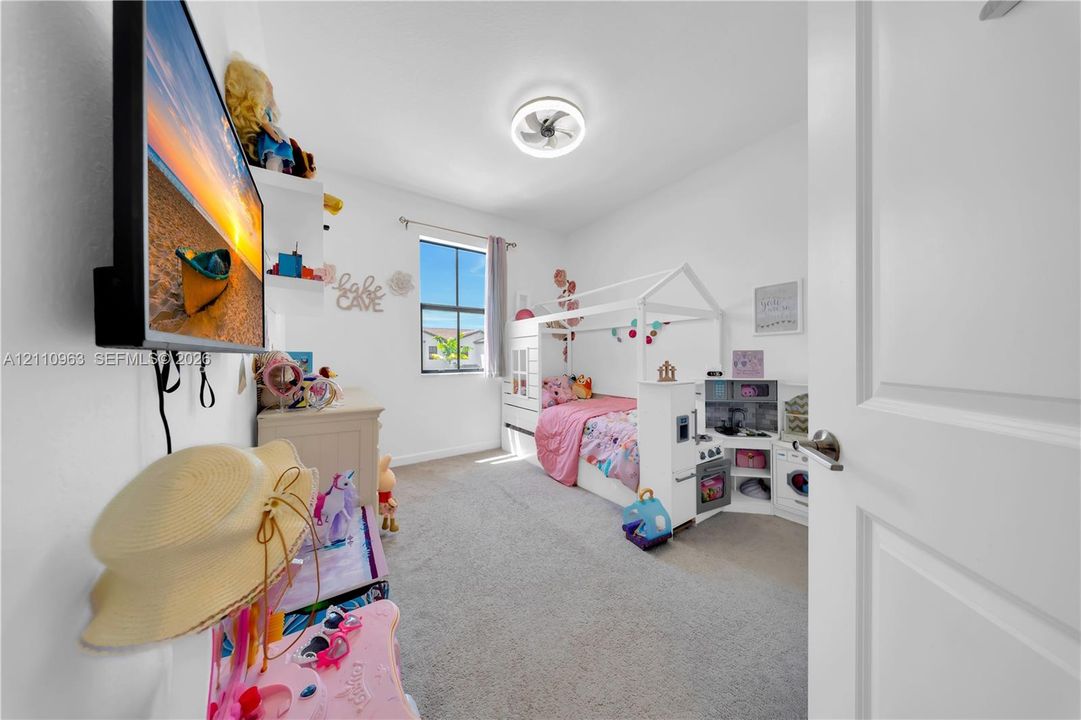 Bedroom featuring wall-to-wall carpeting, single-pane window, built-in shelving, and a modern circular ceiling-mounted light fixture