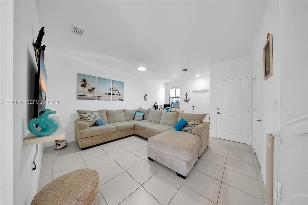 Open-concept interior featuring light-colored floor tiling, neutral wall finishes, recessed lighting, and a multi-panel door