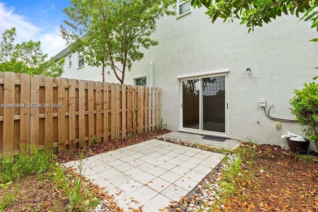 Private fenced yard with a concrete paver patio and sliding glass door access