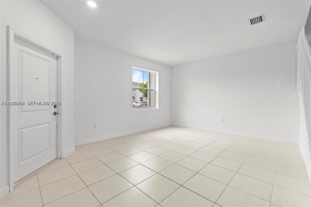 Neutral interior featuring square ceramic tile flooring, crisp white walls, a multi-panel entry door, and recessed lighting