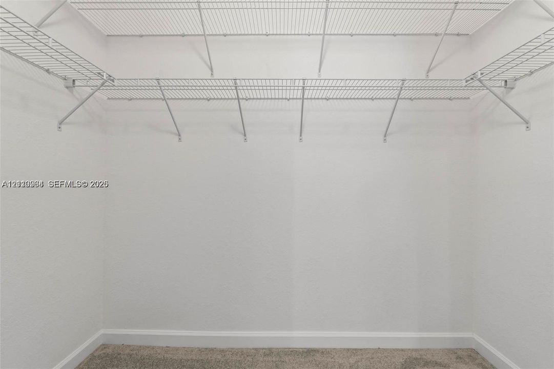 Walk-in closet featuring floor-to-ceiling white walls and white wire shelving