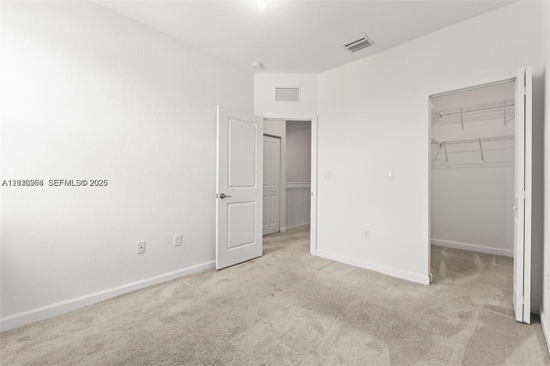 Neutral interior featuring wall-to-wall carpeting, paneled interior doors, and a walk-in closet with integrated wire shelving