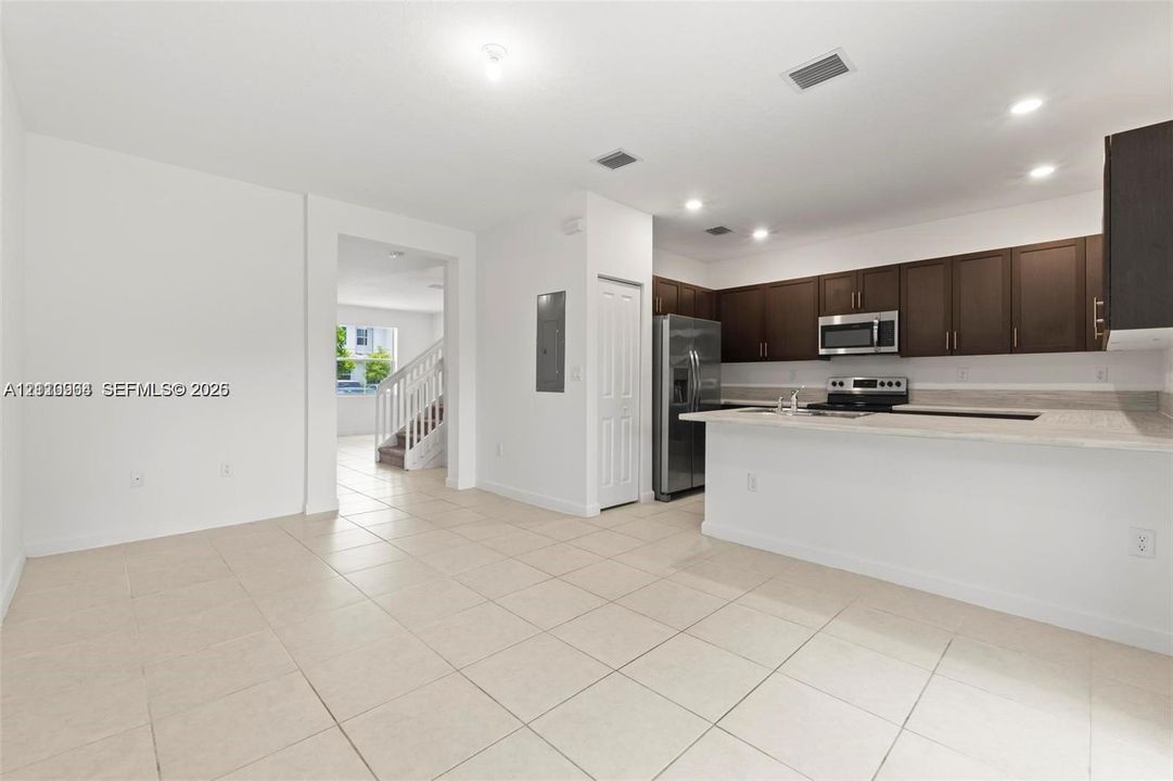 Kitchen featuring dark wood-finish cabinetry, stainless steel appliances, a breakfast bar, and light-toned tile flooring