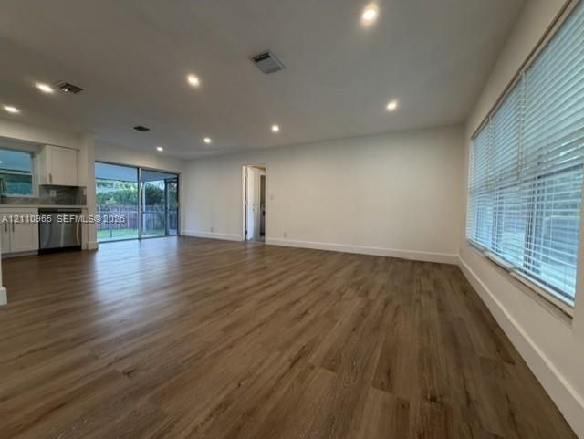 Open-concept area featuring wood-finish flooring, recessed lighting, expansive glass sliding doors, and horizontal window blinds