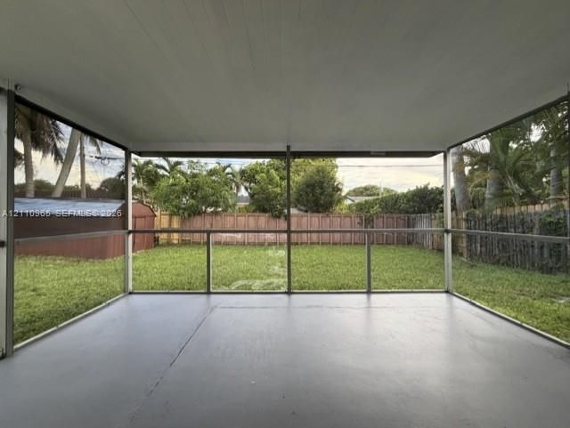 Screened-in porch featuring a concrete floor, painted ceiling, and panoramic mesh screening overlooking a fenced backyard