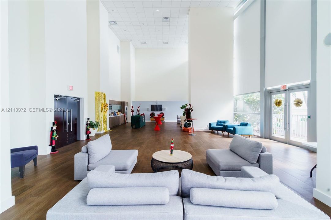 Expansive open-concept space featuring double-height ceilings, wood-finish flooring, floor-to-ceiling windows, and recessed lighting