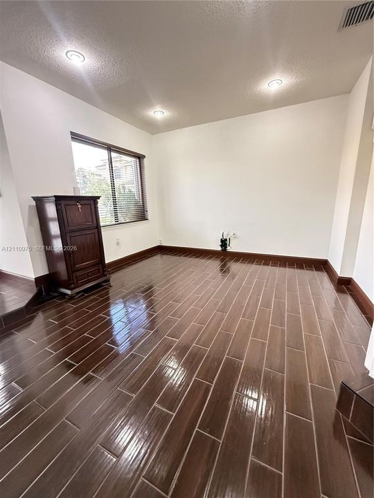 Glossy wood-finish tile flooring, recessed ceiling lighting, and a window with horizontal blinds