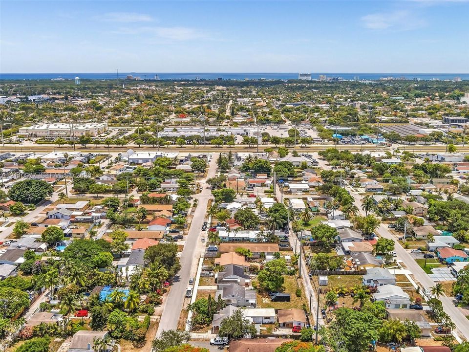 Aerial perspective featuring an established residential neighborhood with mature canopy trees and proximity to the coastline