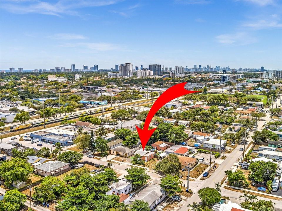 Aerial perspective of a detached single-story residence situated within an urban environment, featuring a hip roof and established surrounding greenery