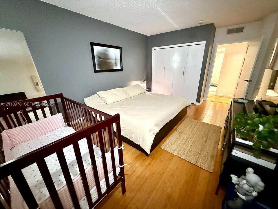 Room featuring wood-finish flooring, a wall-length closet with multi-panel white doors, and painted neutral walls