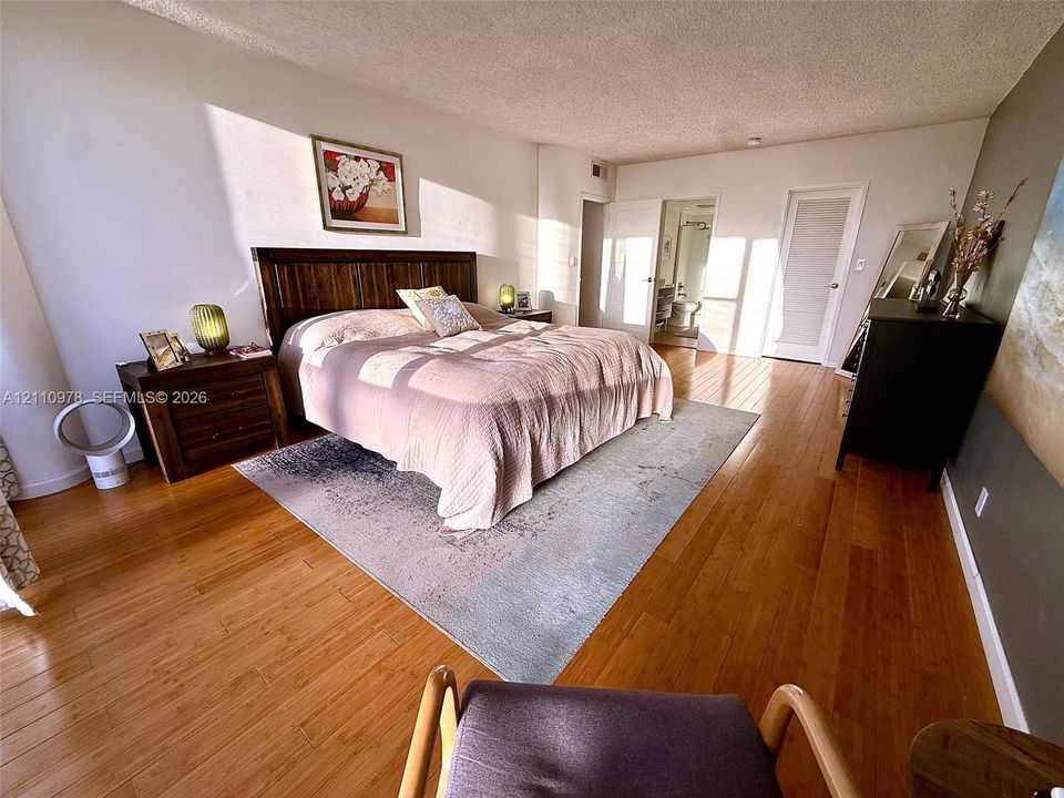 Bedroom featuring wood-finish flooring, two sets of paneled interior doors, and a neutral wall palette