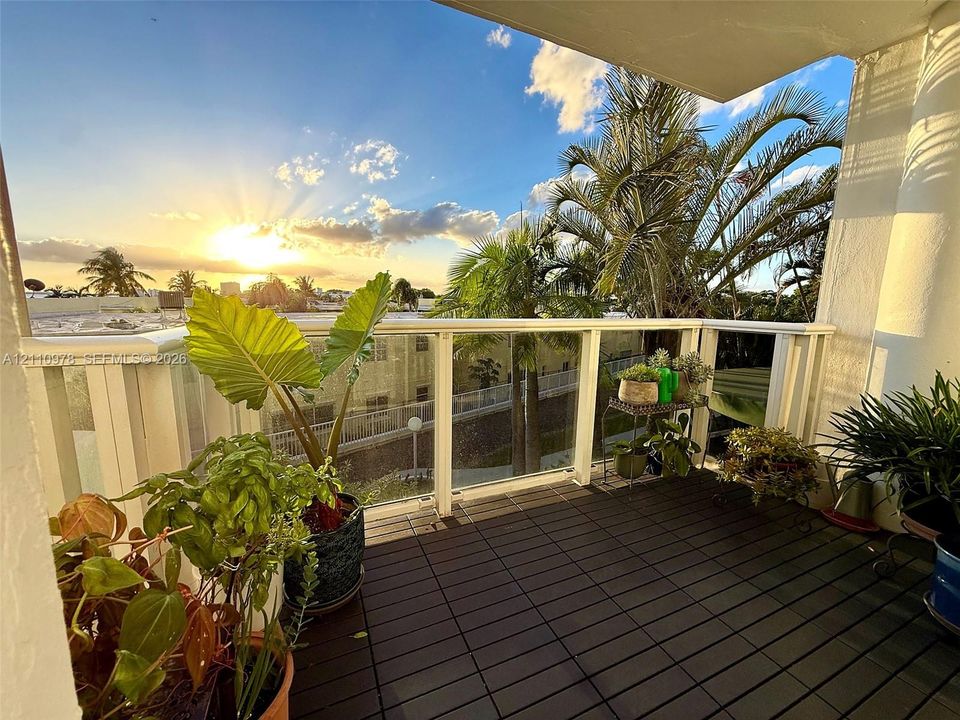Private balcony featuring interlocking deck tiles and a glass-paneled railing