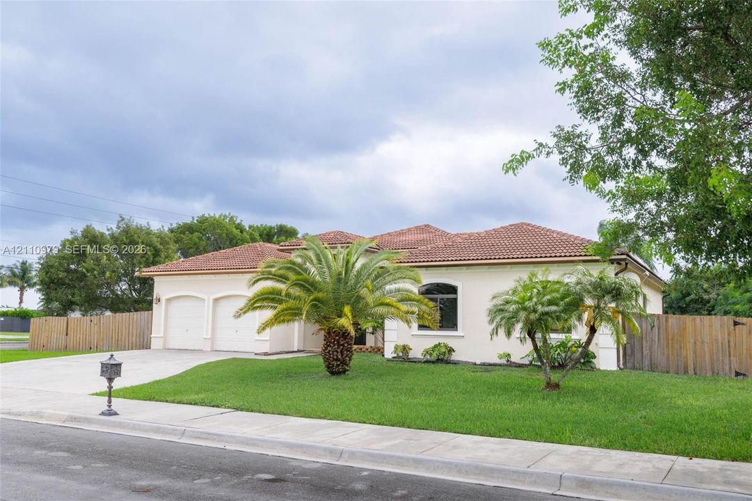 Stucco exterior residence featuring a multi-gabled terracotta tile roof, two-car garage, and arched window detailing