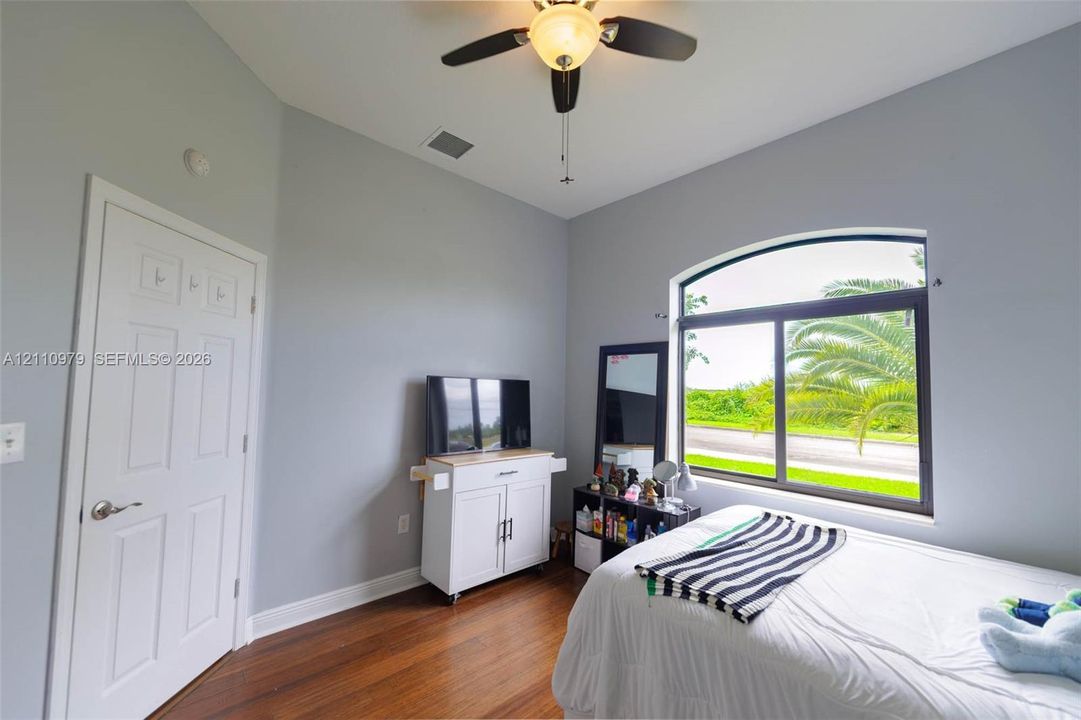Room with vaulted ceilings, wood-finish flooring, and an arched window featuring a dark frame and exterior scenery
