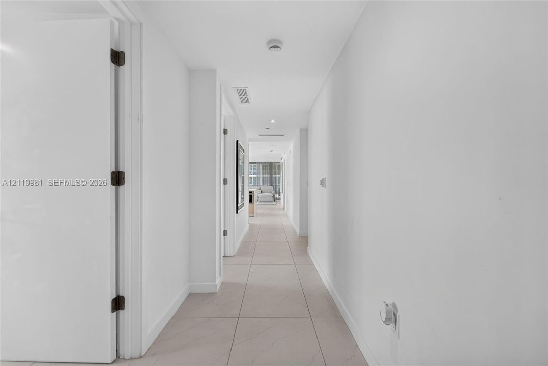 Hallway featuring large-format rectified tile flooring, smooth-finish ceilings, and recessed lighting