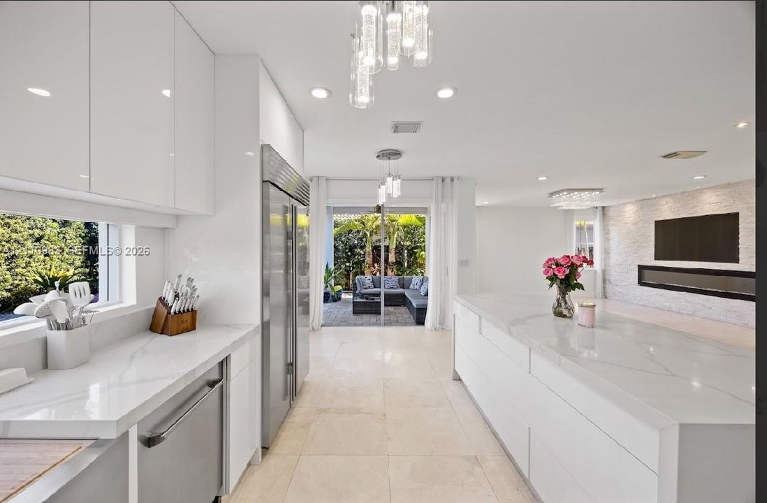 Kitchen featuring high-gloss white cabinetry, quartz countertops, a large center island, stainless steel refrigerator, and recessed lighting