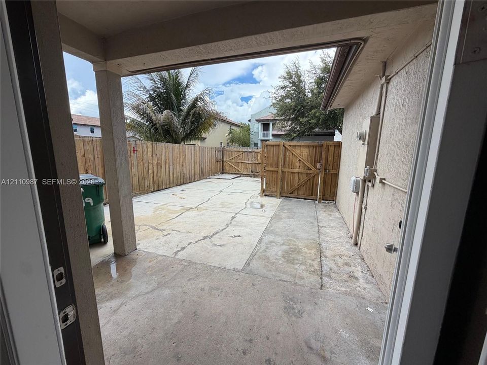 Covered concrete patio with a fenced outdoor area and wood privacy screening