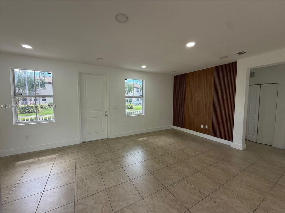 Interior space featuring large-format ceramic tile flooring, recessed lighting, and a decorative wood-slat accent wall