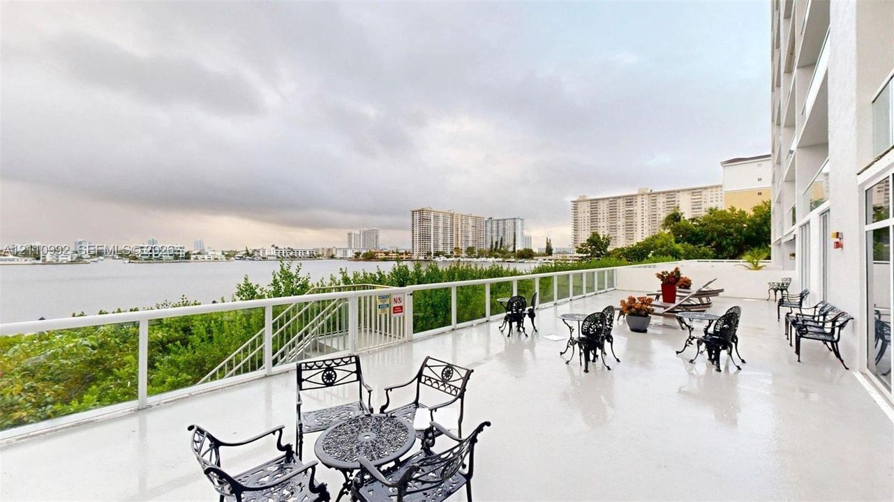 Expansive terrace featuring smooth flooring, metal railings with glass panels, and water-facing orientation