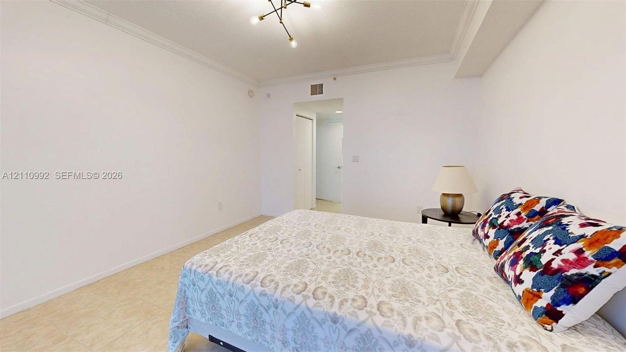 Neutral-toned room featuring neutral ceramic tile flooring, crown molding, and a modern multi-arm light fixture