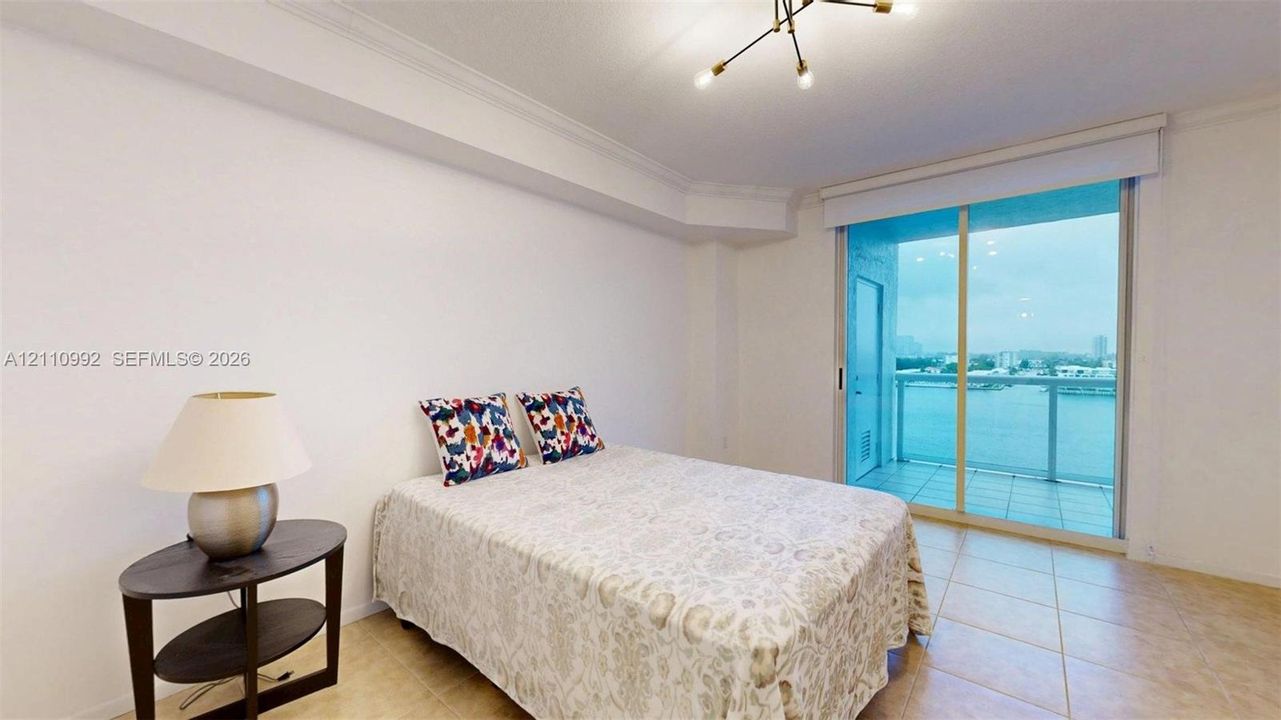 Spacious room featuring neutral tile flooring, crown molding, a modern multi-arm ceiling light fixture, and a large sliding glass door leading to a balcony
