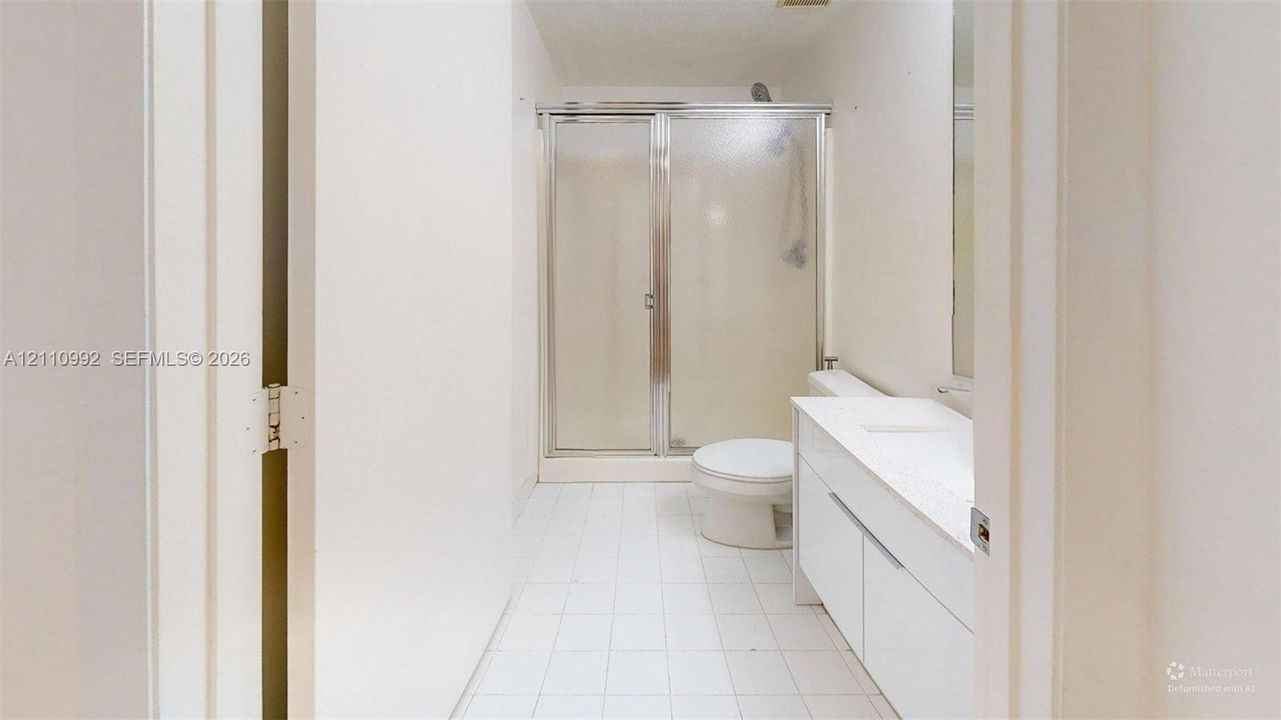 Bathroom featuring a white vanity cabinet with a stone countertop, an integrated sink, a walk-in shower with a glass enclosure, and ceramic tile flooring