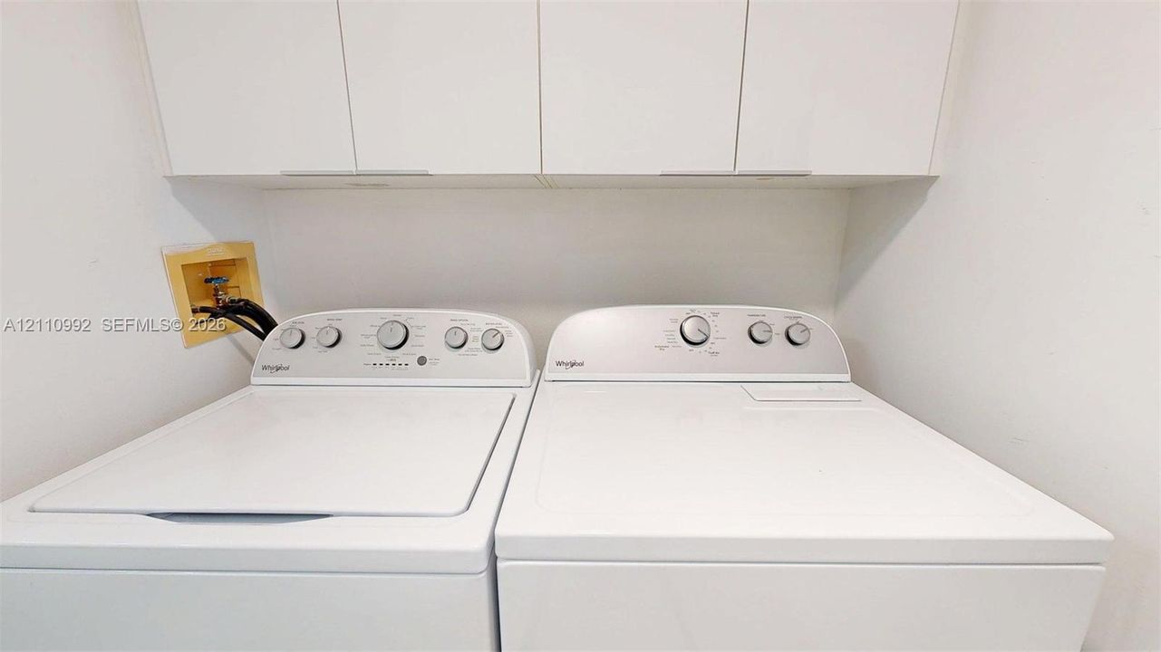 Laundry area featuring white cabinetry and built-in washing machine and dryer