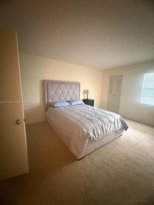 Neutral-toned interior space featuring carpeting, a closet with double-panel doors, and a window with horizontal blinds